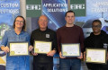 Four Edac staff smiling and holding anniversary certificates