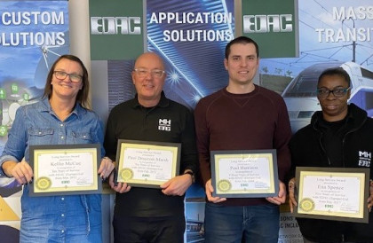 Four Edac staff smiling and holding anniversary certificates